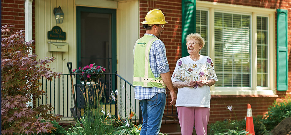 Consumers Energy natural gas worker speaking to a woman in front of her homw